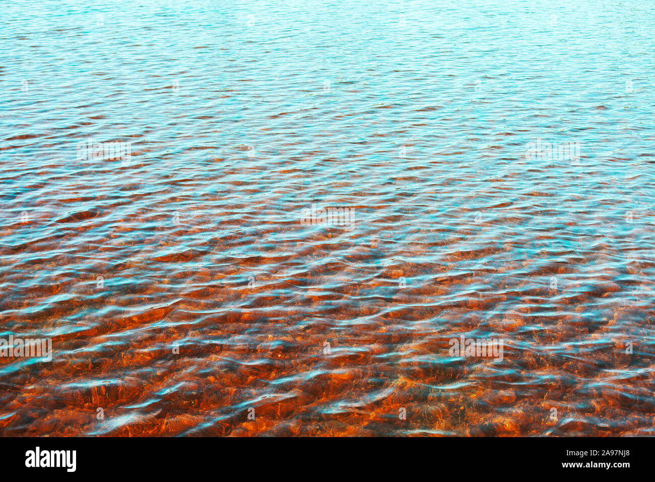 Meer Wasser Oberfläche mit Welligkeit Reflexionen und roten Meeresboden, natürlichen Hintergrund Foto Textur Stockfoto
