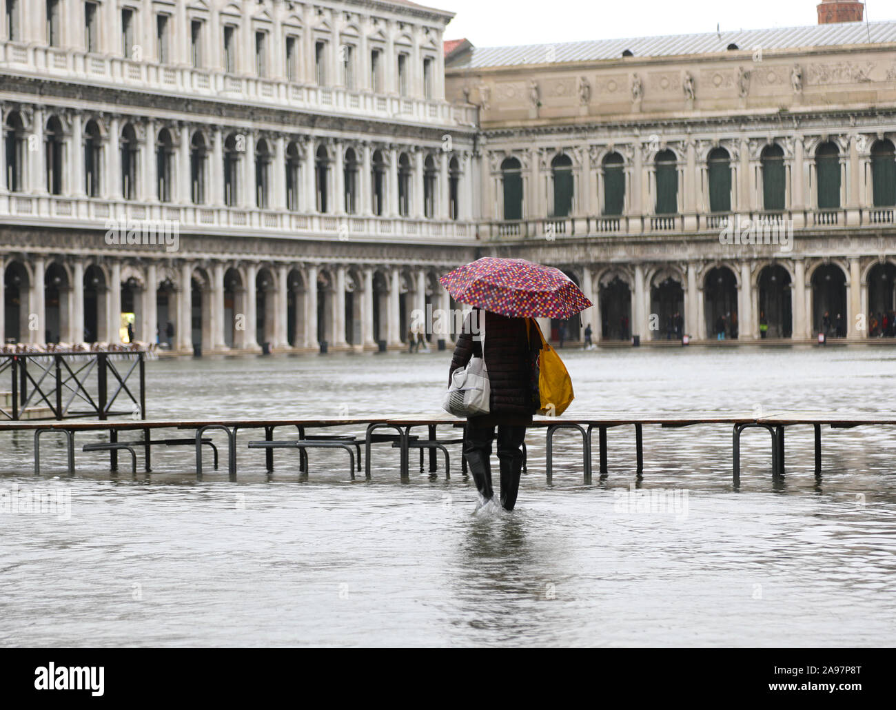 Person mit Regenschirm beim Hochwasser in Venedig in Italien und der Fussgängerzone boardway Stockfoto