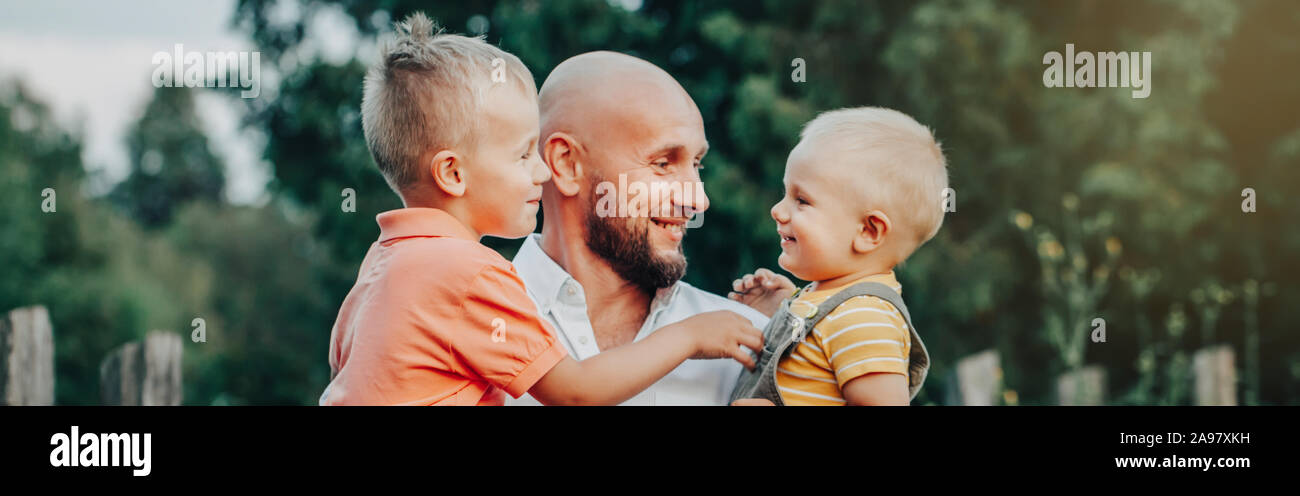 Kaukasische Vater mit Söhnen Jungen im Park im Sommer. Vati holding Kinder Kinder. Authentischen Lebensstil berühren bewegender Moment. Familie leben glücklich Vaterschaft Stockfoto