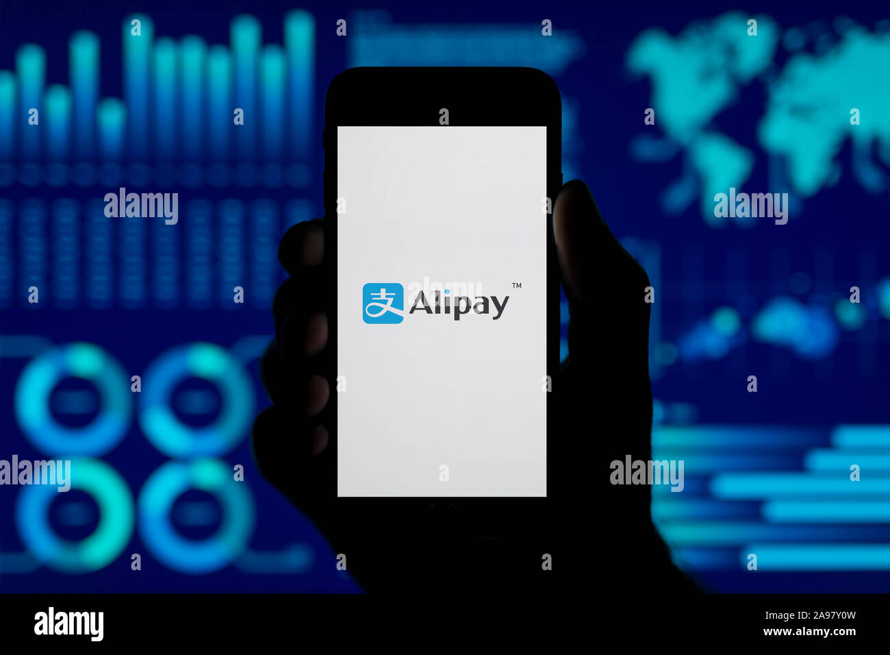 Ein Mann hält ein iPhone, das zeigt die Alipay logo, Schuß gegen eine Visualisierung von Daten im Hintergrund (nur redaktionelle Nutzung). Stockfoto
