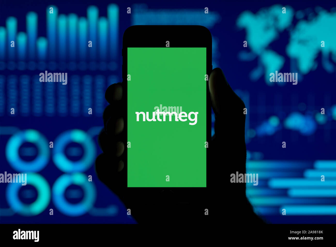 Ein Mann hält ein iPhone, das zeigt die Muskatnuss logo, Schuß gegen eine Visualisierung von Daten im Hintergrund (nur redaktionelle Nutzung). Stockfoto