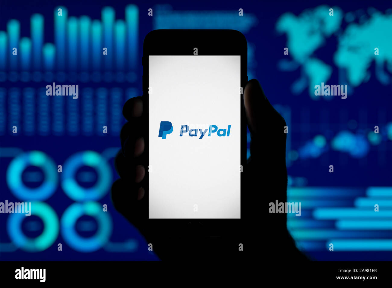 Ein Mann hält ein iPhone, das zeigt das PayPal Logo, Schuß gegen eine Visualisierung von Daten im Hintergrund (nur redaktionelle Nutzung). Stockfoto