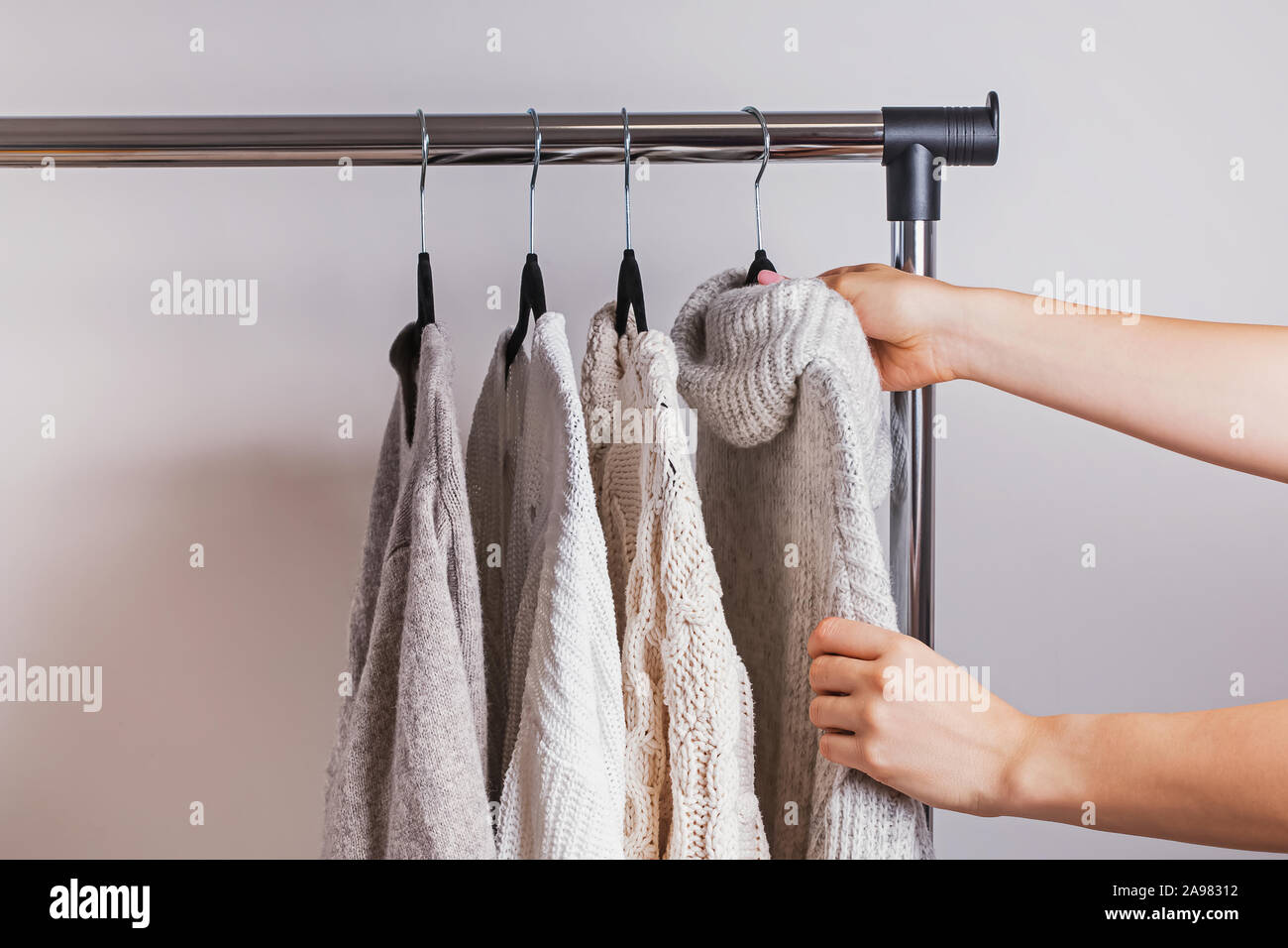 Frau Wahl der warmen gestrickten Pullover aus ihrem minimalistischen Kleiderschrank. Stockfoto