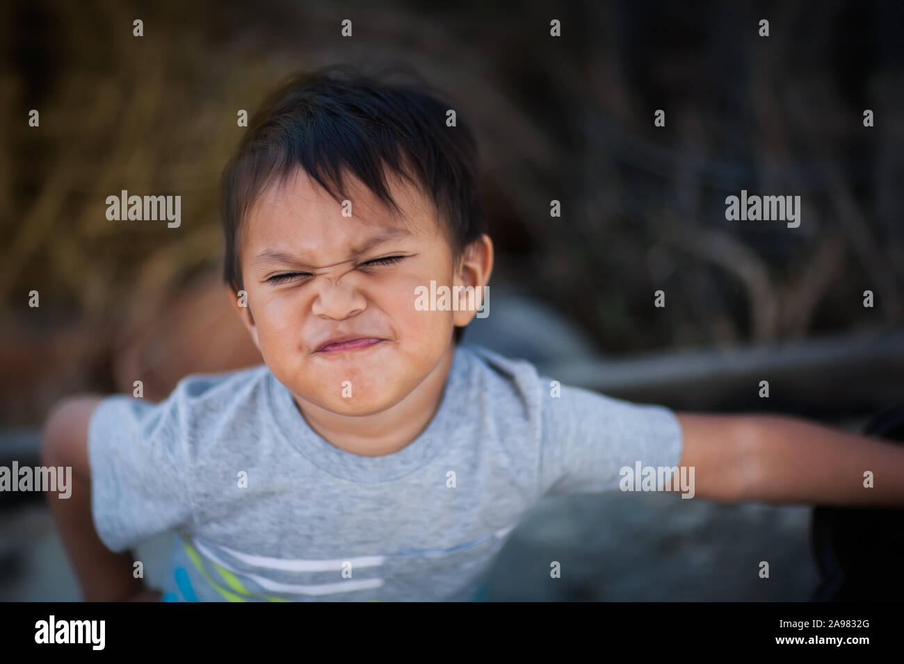 Ein kleiner Junge zum Ausdruck aufgebracht und unkooperative Haltung, indem Sie einen Umgekippten Gesicht und konfrontative Körper Haltung. Stockfoto