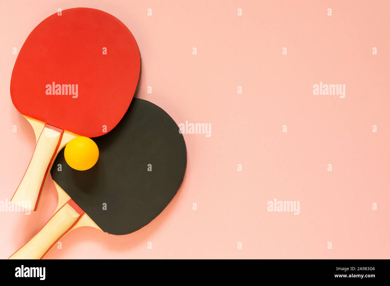 Schwarz und Rot Tennis ping pong Schläger und orange Kugel auf einem rosa Hintergrund isoliert, Sport Ausrüstung für Tischtennis Stockfoto