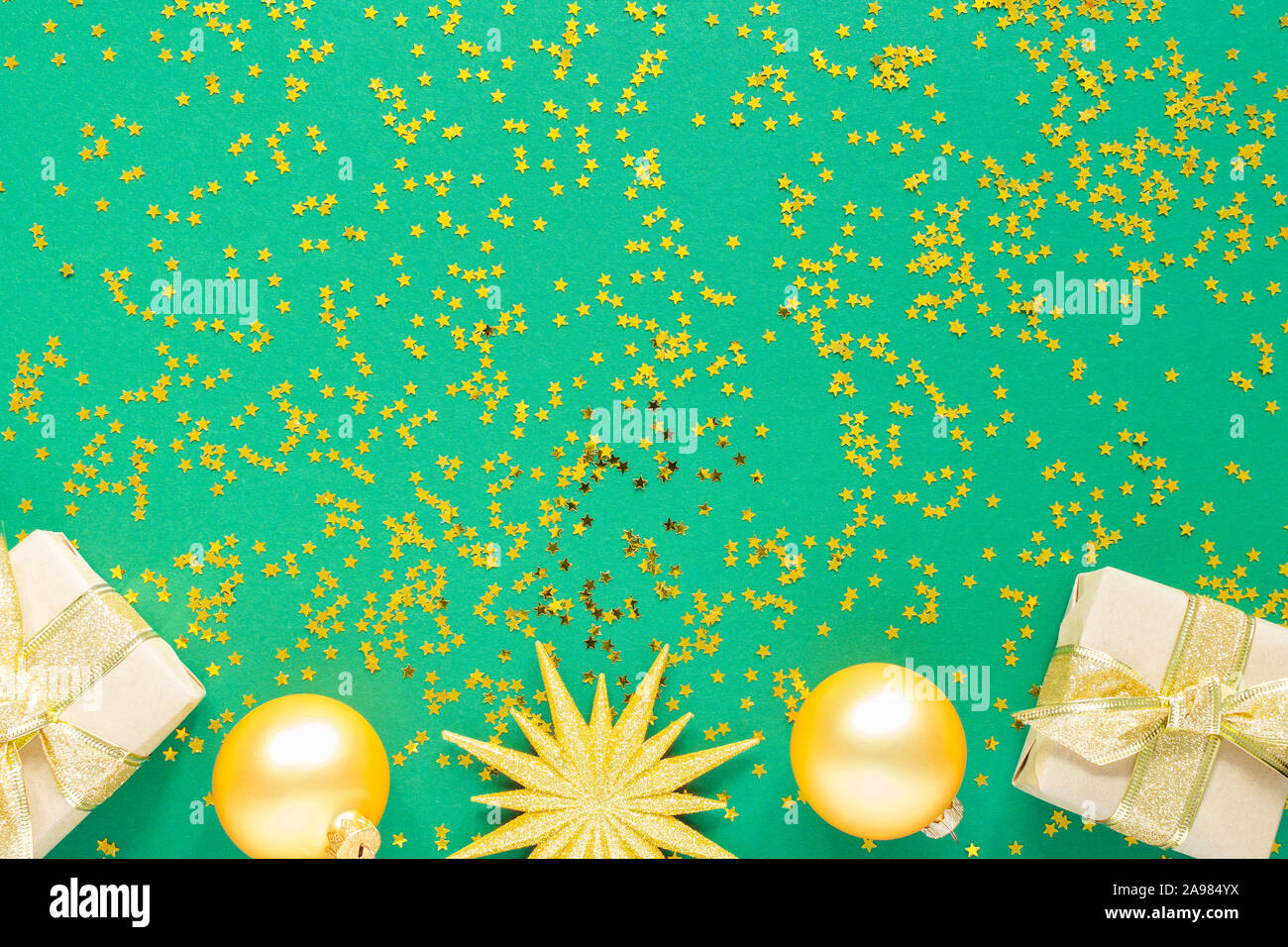Urlaub Hintergrund, gold Weihnachtskugeln und Geschenkboxen auf grünem Hintergrund mit Glitter gold Sterne, Flach, Ansicht von oben Stockfoto