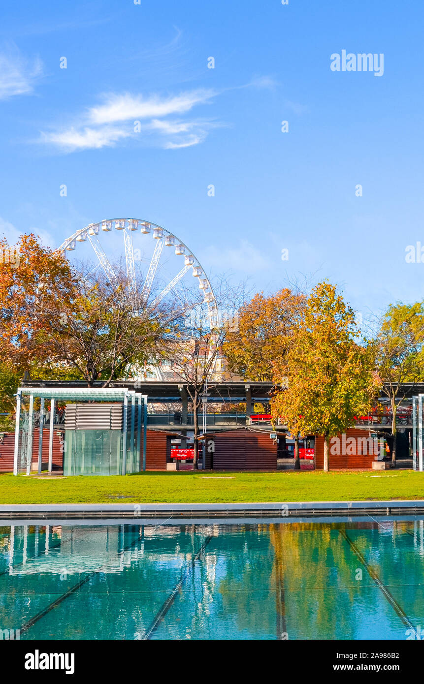 Budapest, Ungarn - Nov 6, 2019: Straßen der Ungarischen Hauptstadt mit Bäumen im Herbst Farben. Wasser aus Brunnen im Vordergrund. Budapest Auge im Hintergrund. Europas größtes Riesenrad. Stockfoto