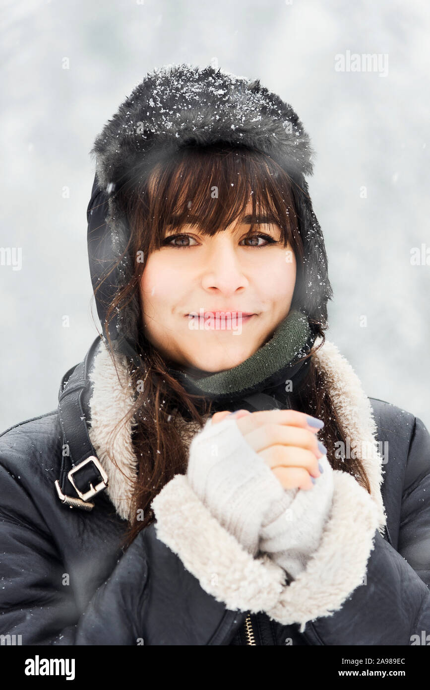 Porträt einer kaukasischen weiß Frau unter Blizzard mit Hut, Mantel und knallt. Mit Blick auf die Kamera. Stockfoto