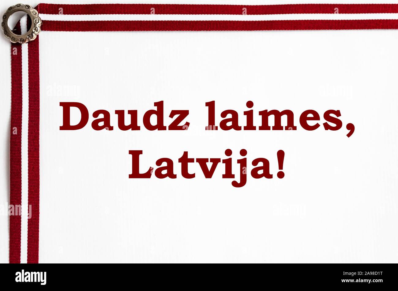 Farbband in die lettische Flagge Farben und Lettischen traditionelle Brosche auf weißem Hintergrund mit Glückwunschschreiben' großes Glück, Lettland!". Stockfoto