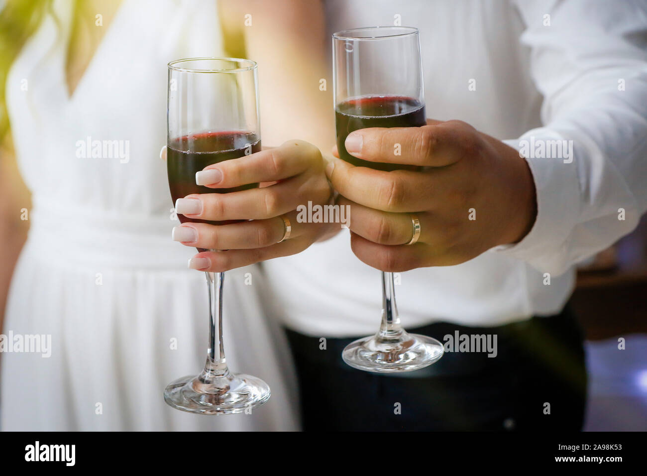 Hände Detail mit Hochzeit Ringe und Weingläser - pflegt Toast - Goldene Hochzeit Ringe Stockfoto