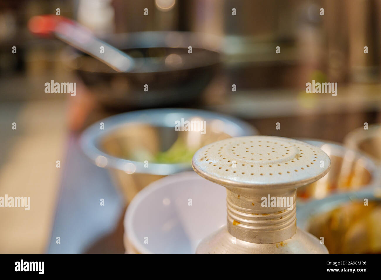 Nahaufnahmen und Makro Anzeigen an der Oberseite des Metall, Weiß Thai pfefferstreuer oder Schleifer und Unschärfe Hintergrund der Küche im Restaurant. Stockfoto