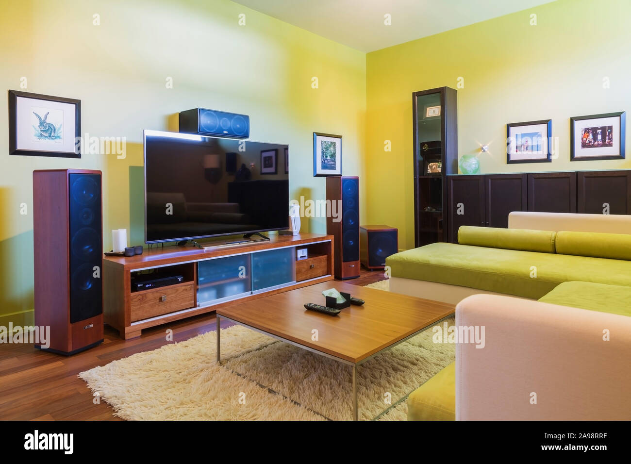 TV-Raum mit Home Entertainment Sound System, kanariengelb Sofagarnitur, Holz und Chrom Couchtisch, weiß shag Teppich in einem luxuriösen Haus Stockfoto