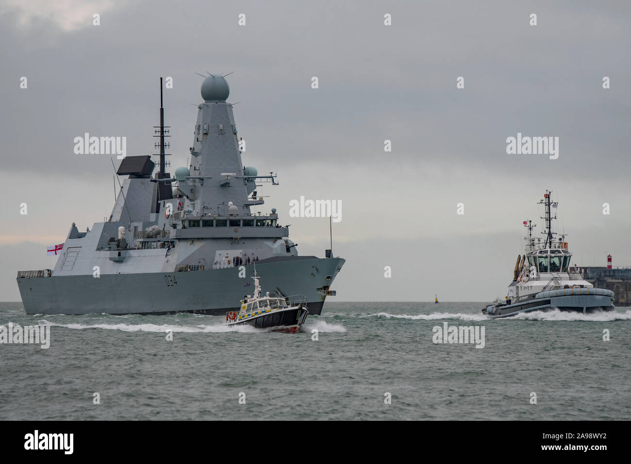 Die Royal Navy gewagte Klasse air defence Zerstörer HMS Diamond (D 34) wird von einem Schlepper und Polizei Boot in Richtung Portsmouth, Großbritannien auf 6/12/18 begleitet. Stockfoto