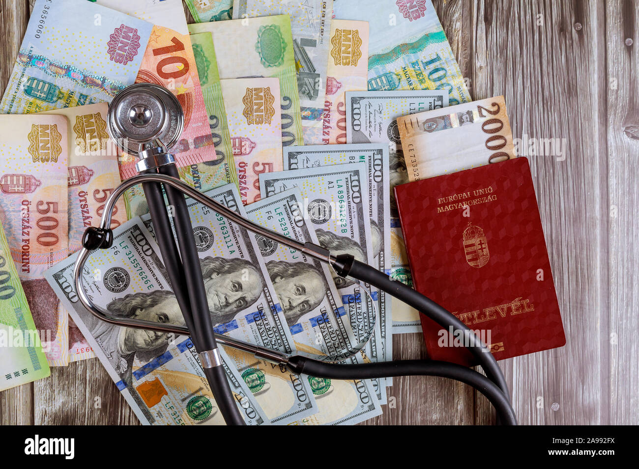 Ungarische Pässe und andere ungarische Forint Banknoten mit amerikanischen Dollar Geld in die medizinische Stethoskop auf Schreibtisch Stockfoto