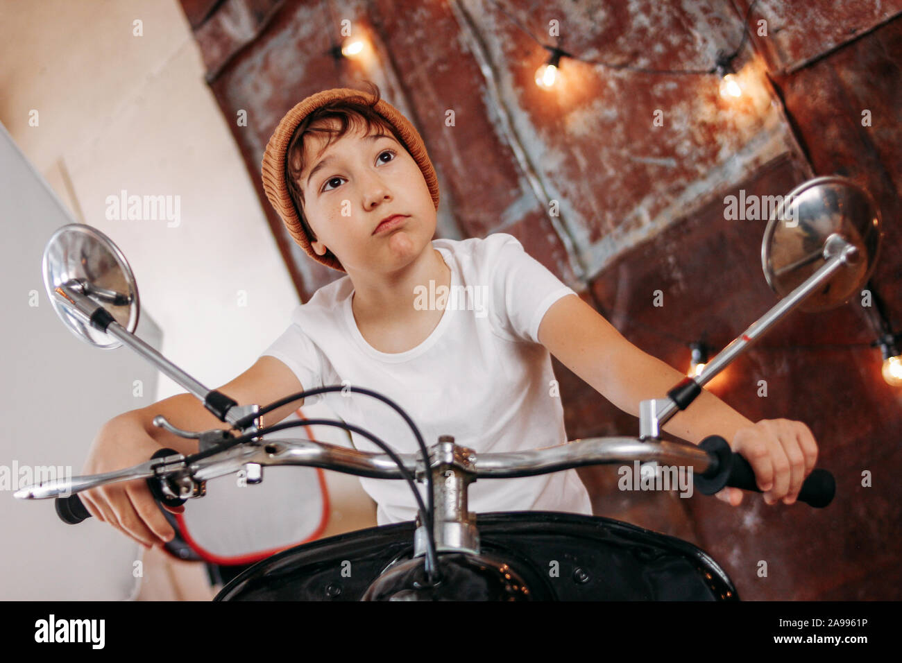 Funny cute tween Boy auf Motorrad präsentiert sich selbst als Erwachsener und cool Stockfoto