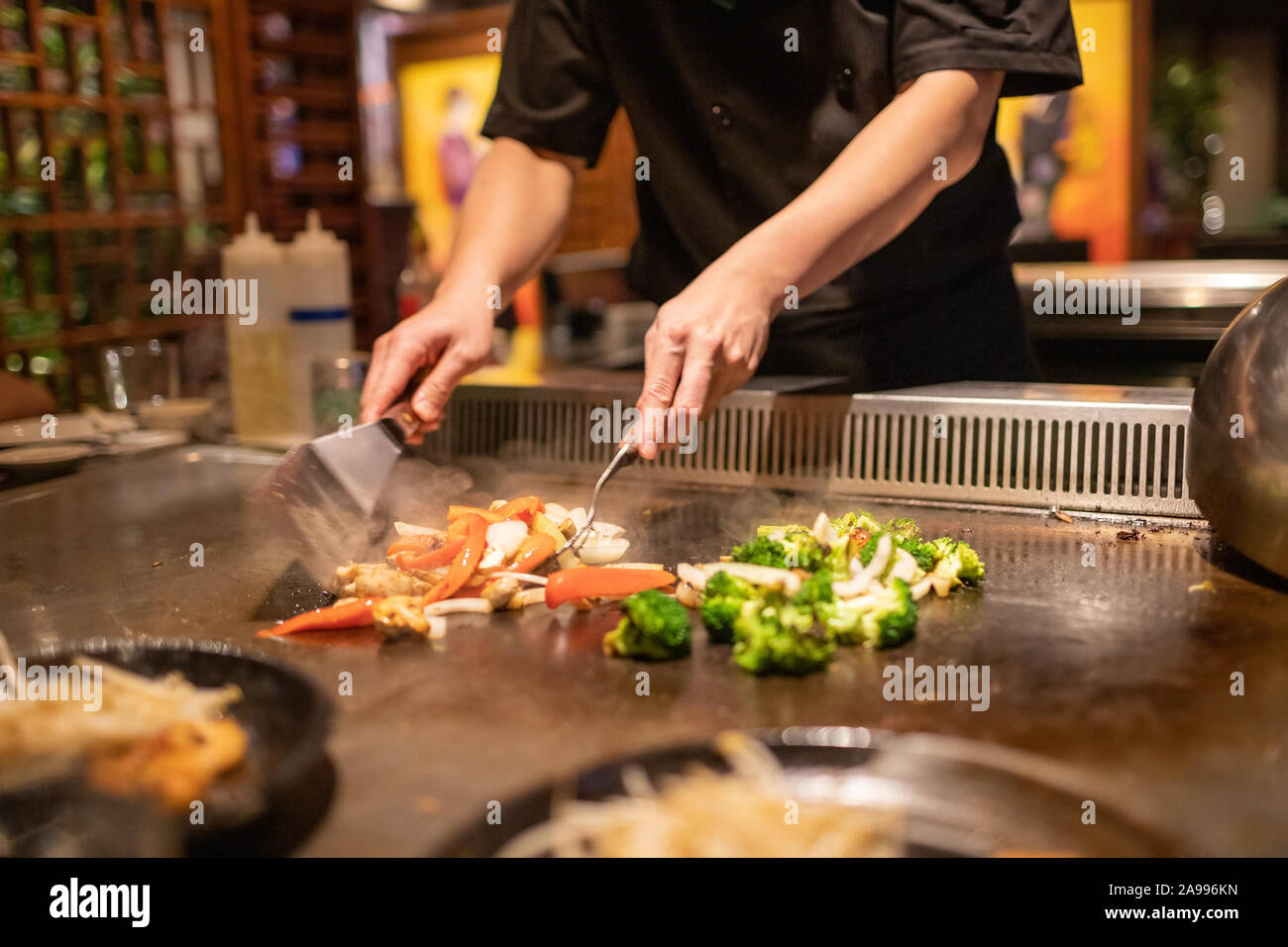 Teppanyaki Küchenchef bereiten Japanische Küche auf heißem Metall Platte durch Schneiden von Gemüse Stockfoto
