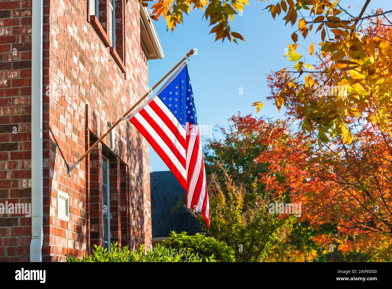 Patriotische amerikanische Flagge schwenkten vor einem Backstein home an einem sonnigen Herbsttag. Stockfoto