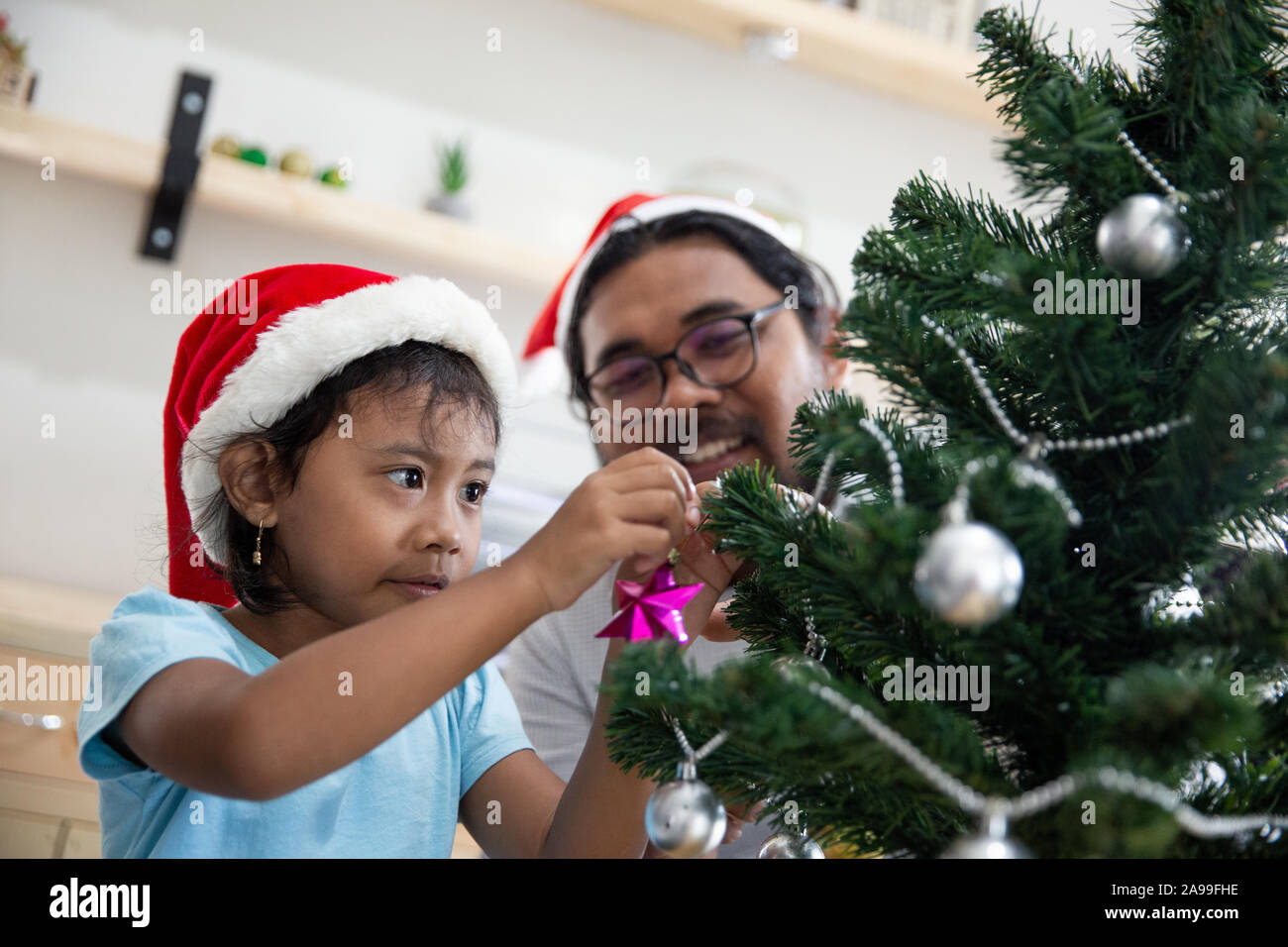 Gerne Vater Arbeiter schmücken Weihnachtsbaum mit seiner Tochter Stockfoto