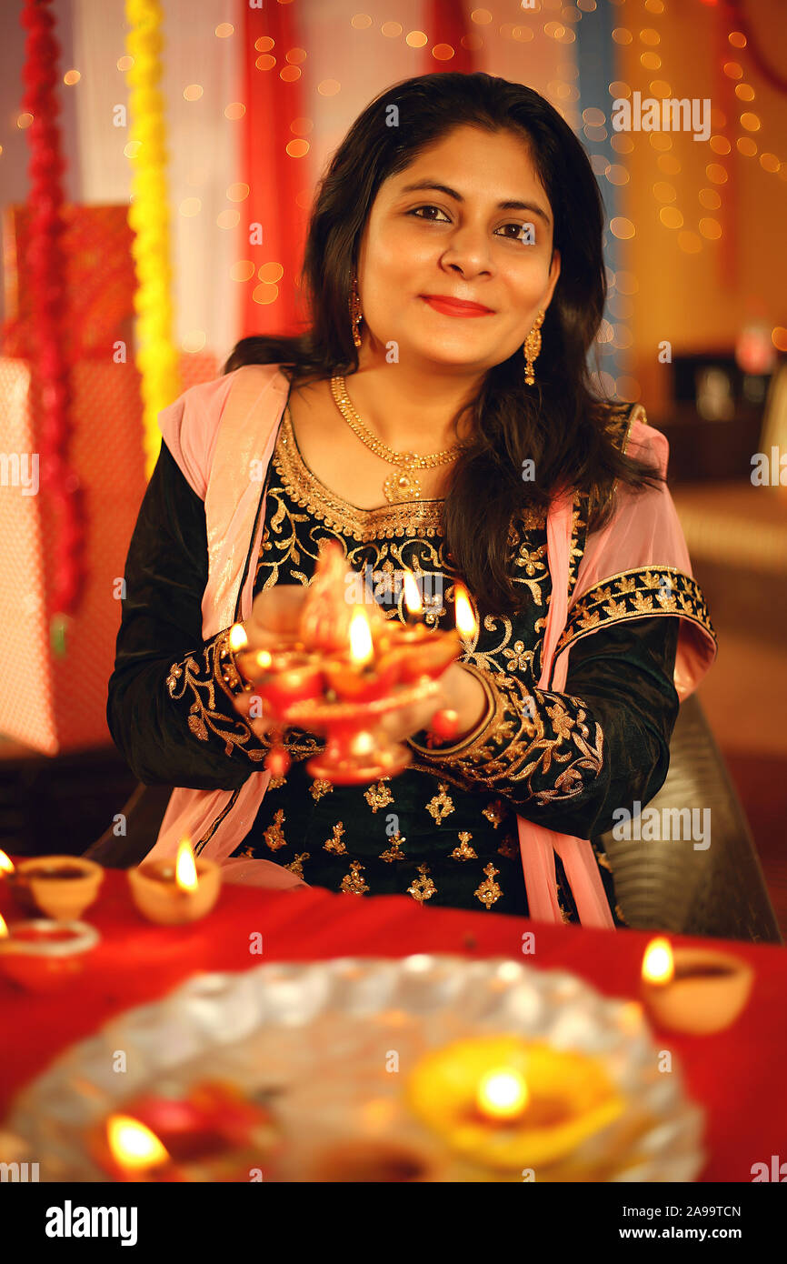 Eine schöne junge Frau in der traditionellen indischen Sari Kleid mit einem Öl lampe licht oder Diya in dekorativen Hintergrund anlässlich von Diwali Stockfoto