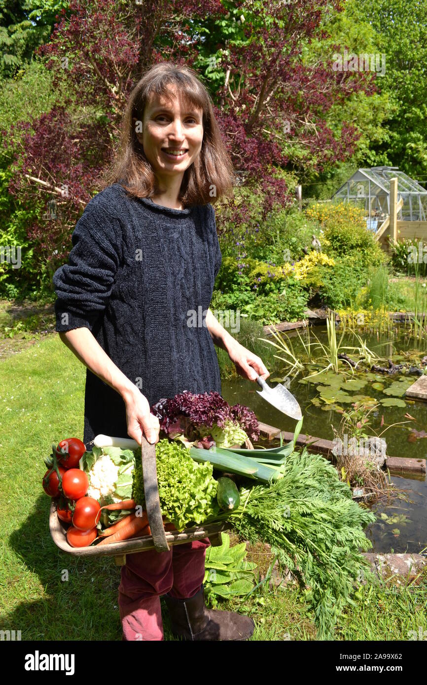Dame mit einem trug voller Gemüse in einem Garten Stockfoto