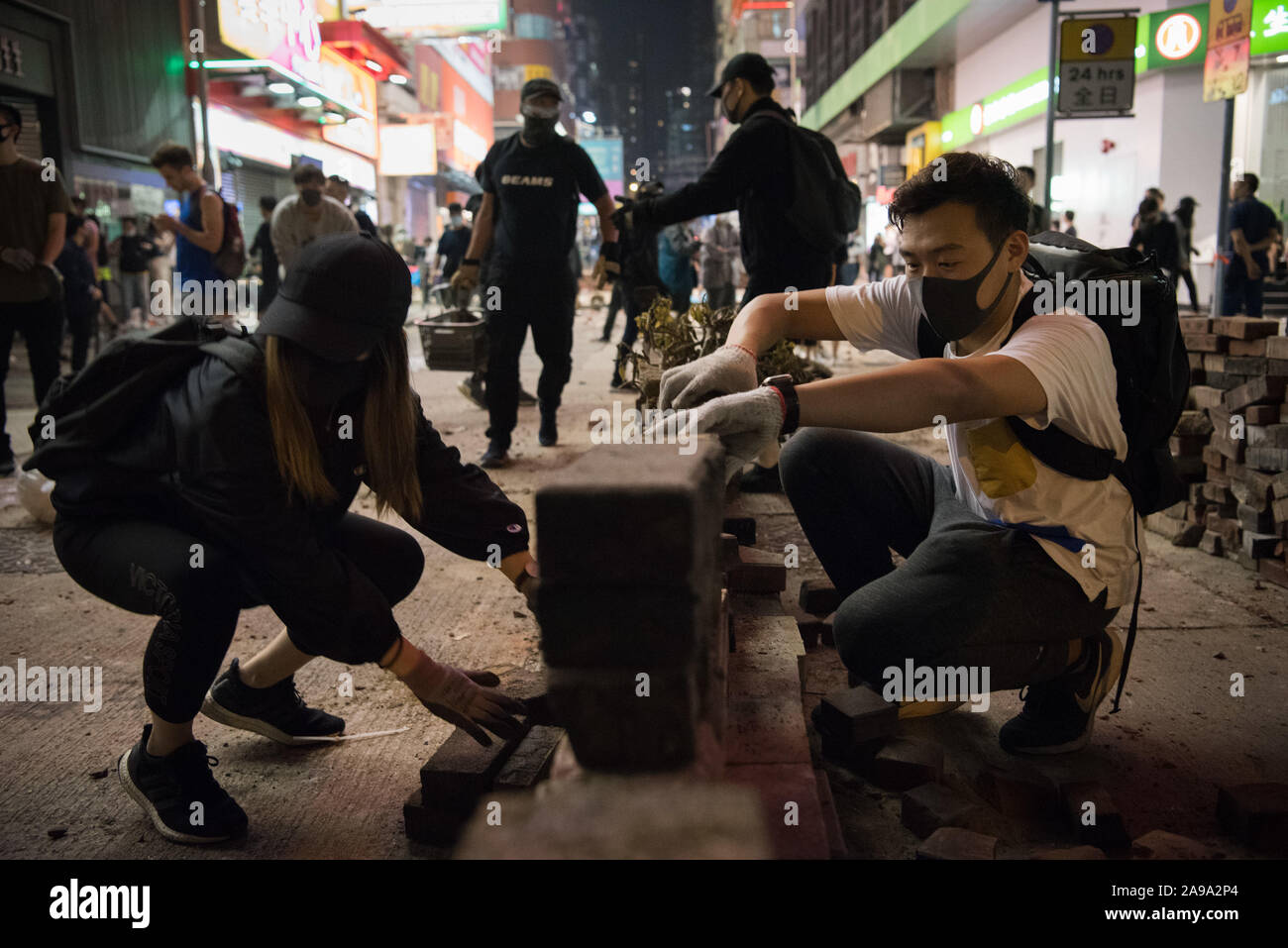 Die Demonstranten, um Steine Barrikaden in Mong Kok zu errichten. Die Protestbewegung hat eine Spitze in der Gewalt seit dem Tod von Student Alex Chow am 9. November gesehen, nach einem Sturz aus dem Sims auf einem Parkplatz während angeblich Flucht Gas durch die Polizei feuerte Tränengas. Trotz der umstrittenen Auslieferung Rechnung, die ursprünglich funkte die Proteste formell zurückgezogen, Demonstranten weiter auf Chief Executive Carrie Lam zu nennen Ihre restlichen Forderungen, die umfasst das allgemeine Wahlrecht, eine unabhängige Untersuchung über die Brutalität der Polizei, Rückzug des Wortes 'Zusammenrottung' zu beschreiben, zu erfüllen Stockfoto