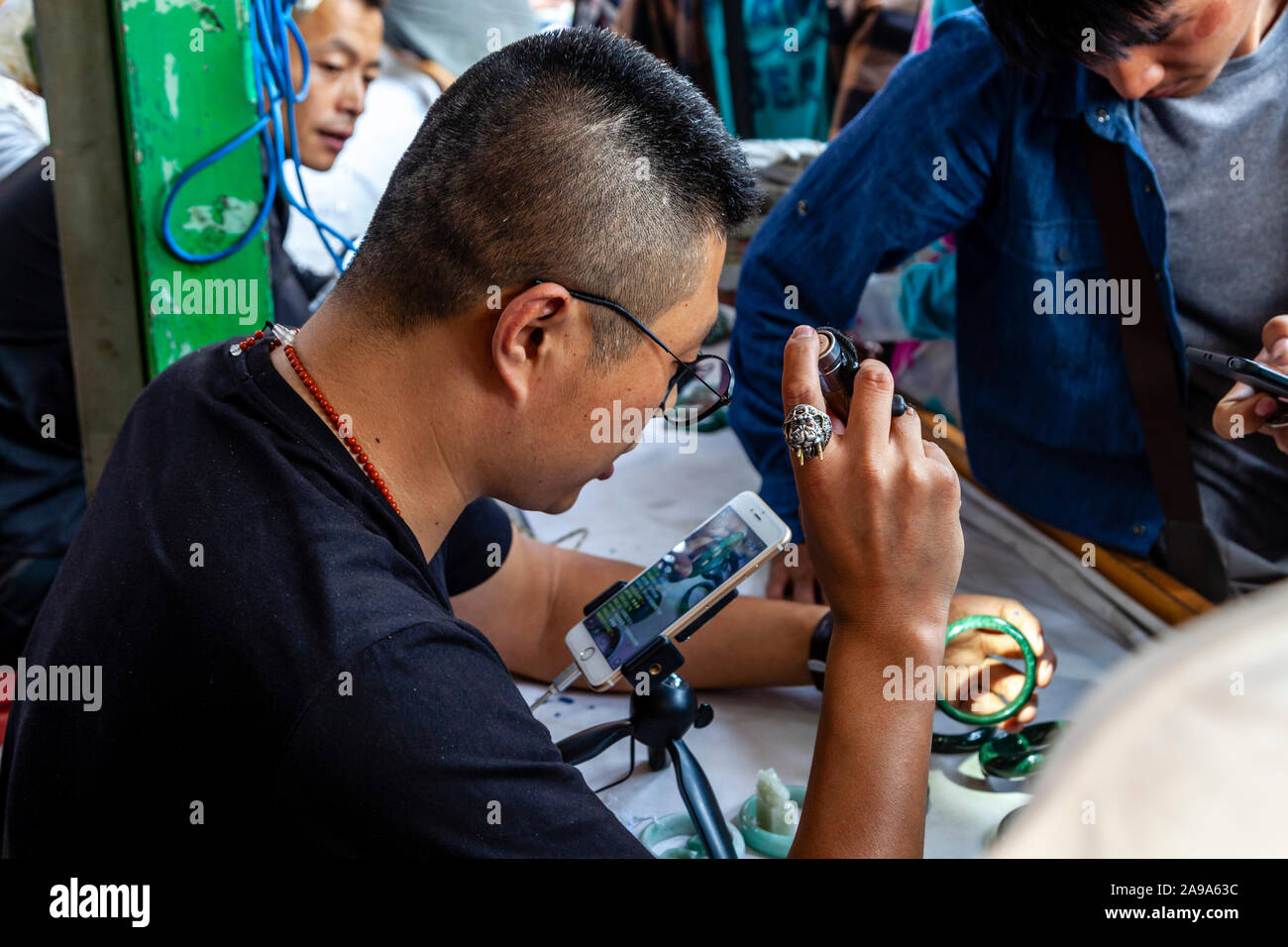 Ein Händler Prüfung Jade Steine an der Jade Market, Mandalay, Myanmar. Stockfoto