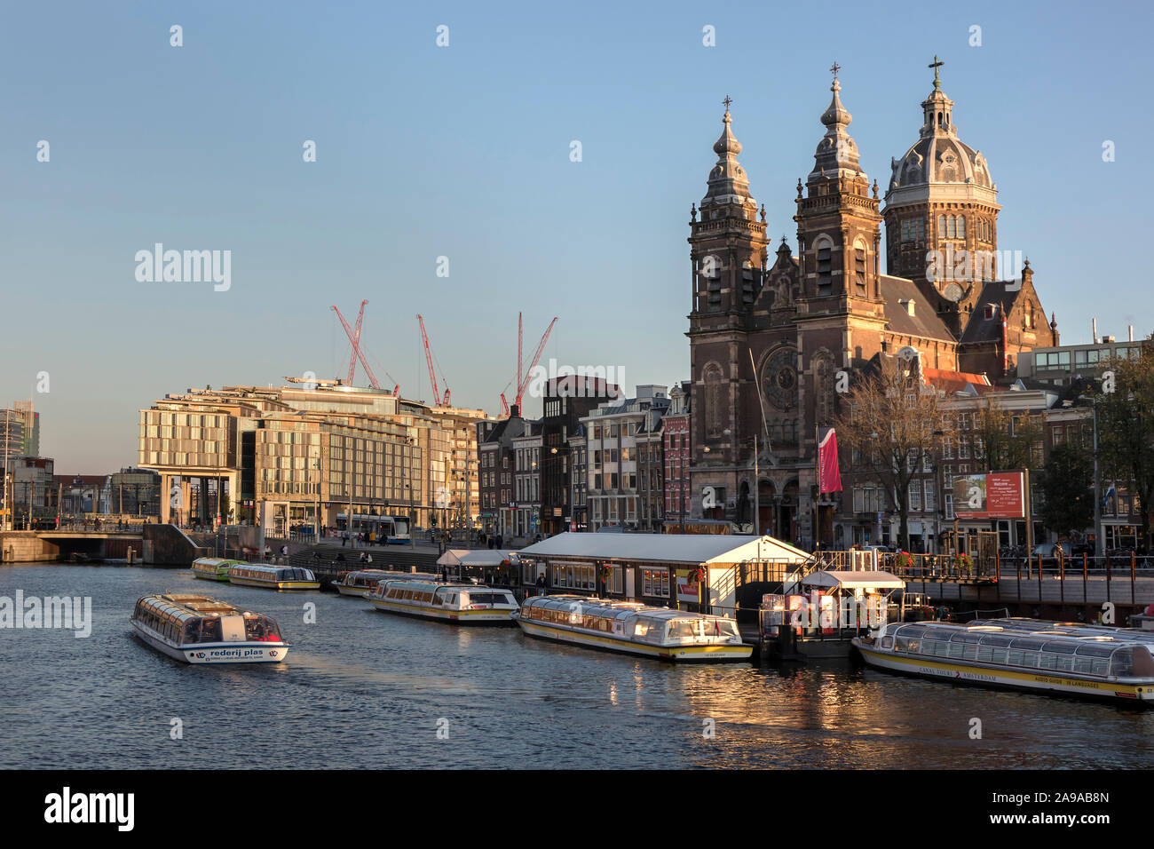 Amsterdam, Holland - Oktober 10, 2019: St. Nikolaus Basilika an der Prins Hendrikkade nahe dem Oudezijds Kolk Wasser bei Sonnenuntergang Stockfoto