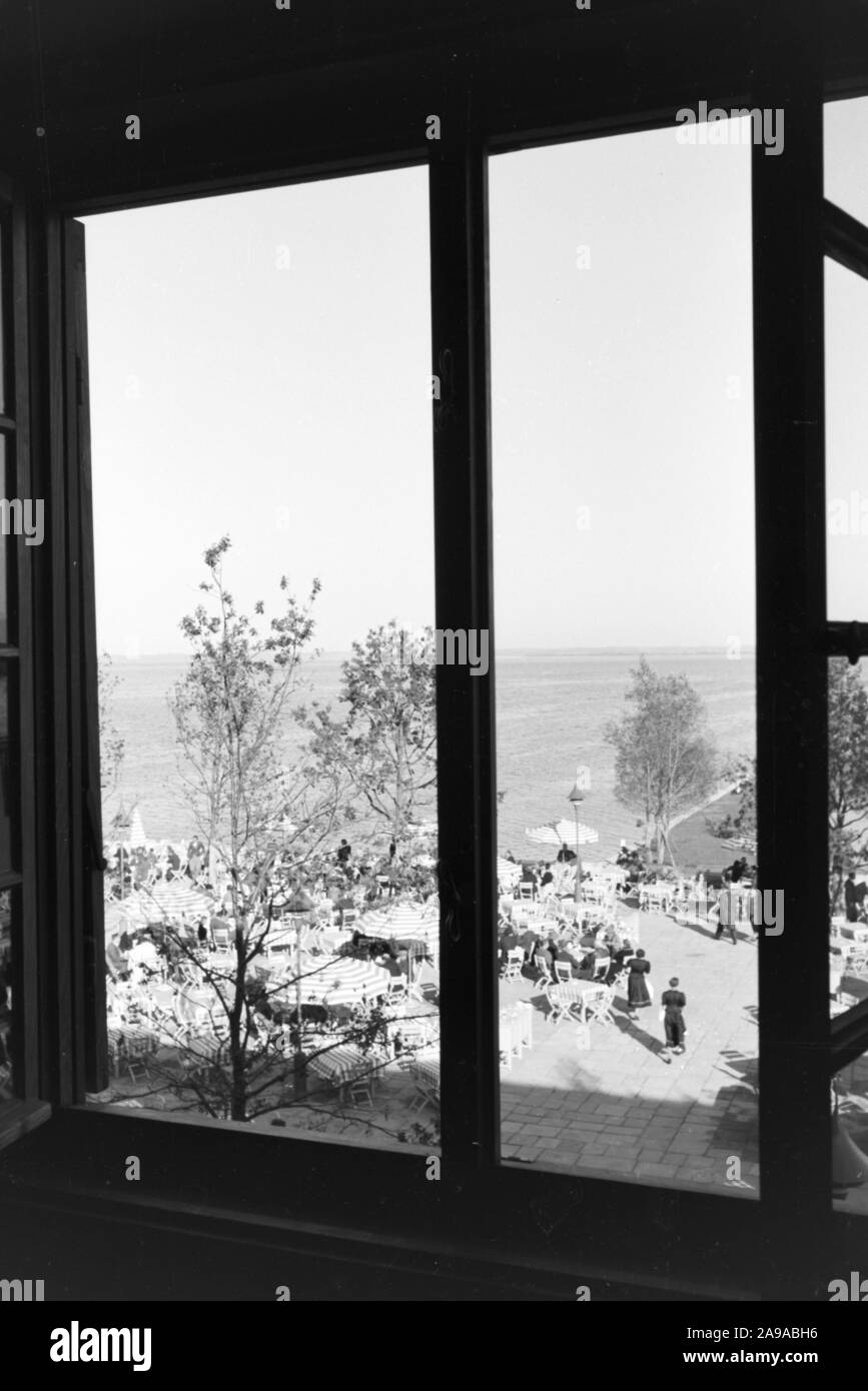 Blick aus dem Fenster auf ein Café Terrasse am Chiemsee, Deutschland 1930. Stockfoto