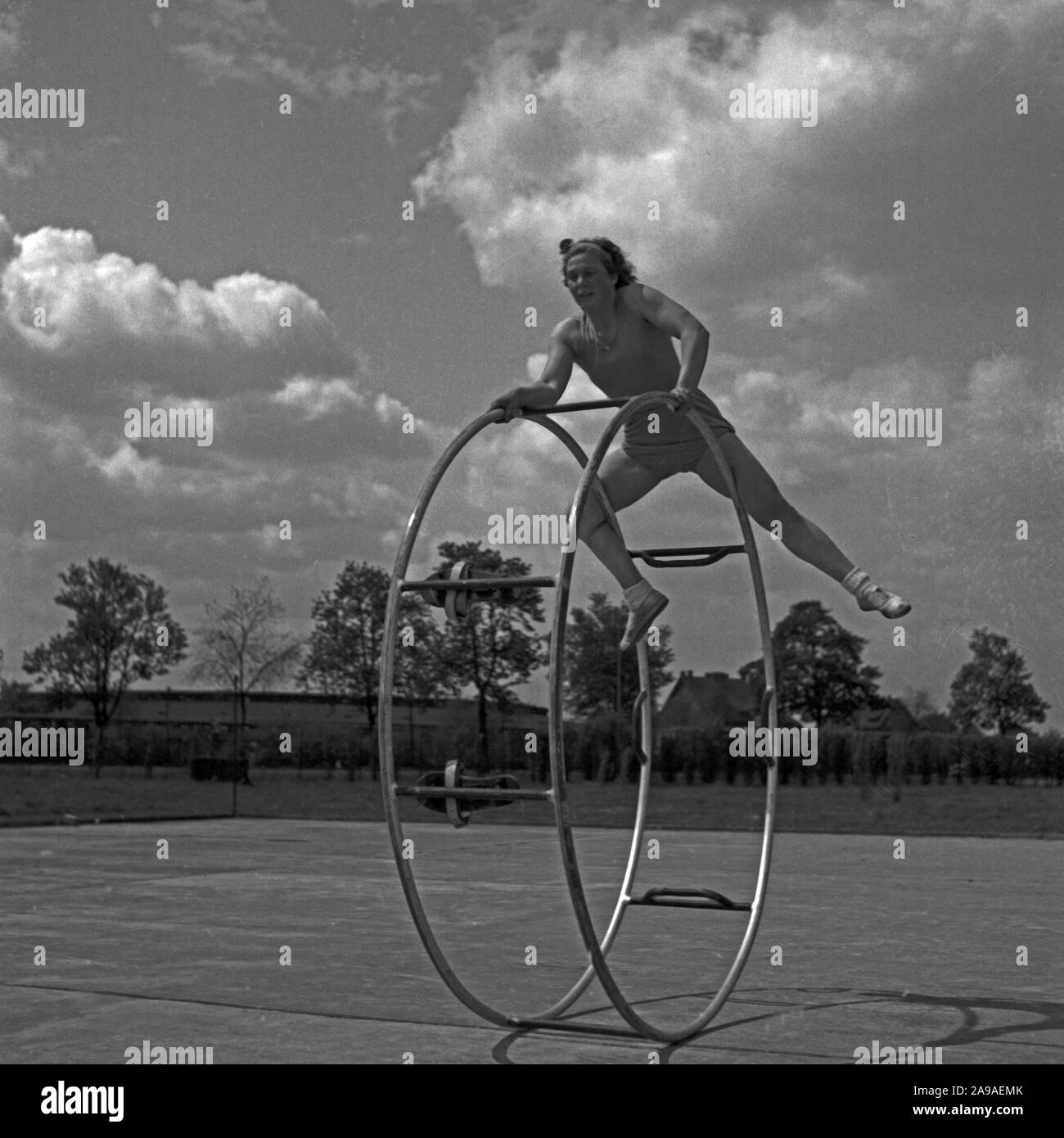 Eine junge Frau, die mit ihrem gymwheel auf einem Sportplatz, Deutschland 1930. Stockfoto