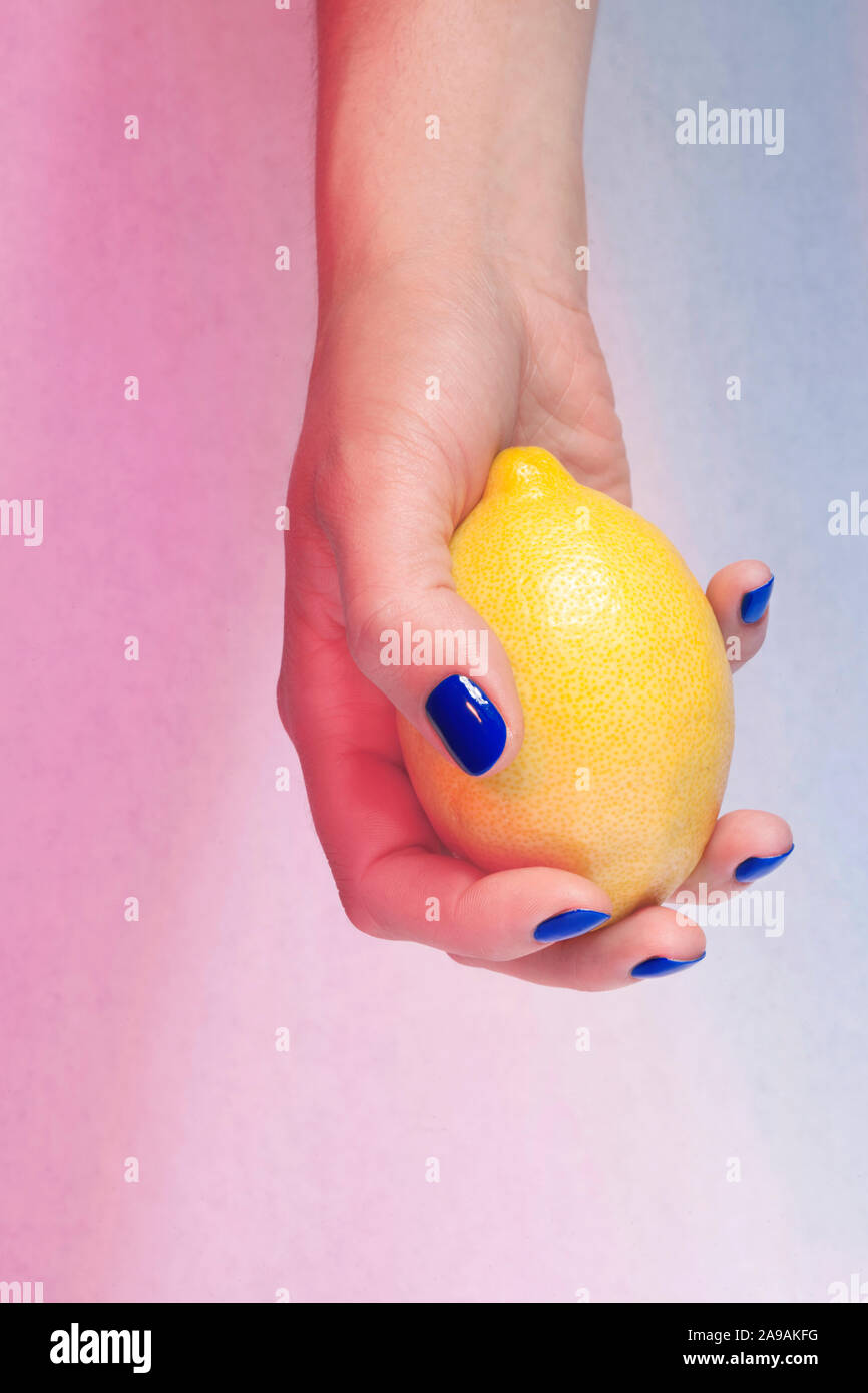 Netz manucurées de Bleu Mieter-/jouant avec un Citron jaune/gepflegte Hände blau Holding/spielen mit einer gelben Zitrone Stockfoto