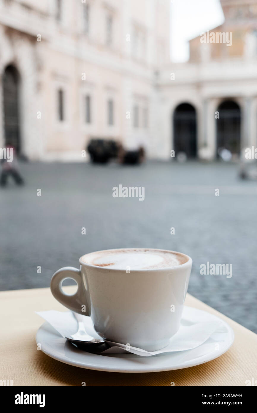 Nahaufnahme von einem Cappuccino in einem weißen Keramik Schale serviert, auf eine Tabelle in einer Outdoor Terrasse eines Cafés in Rom, Italien Stockfoto