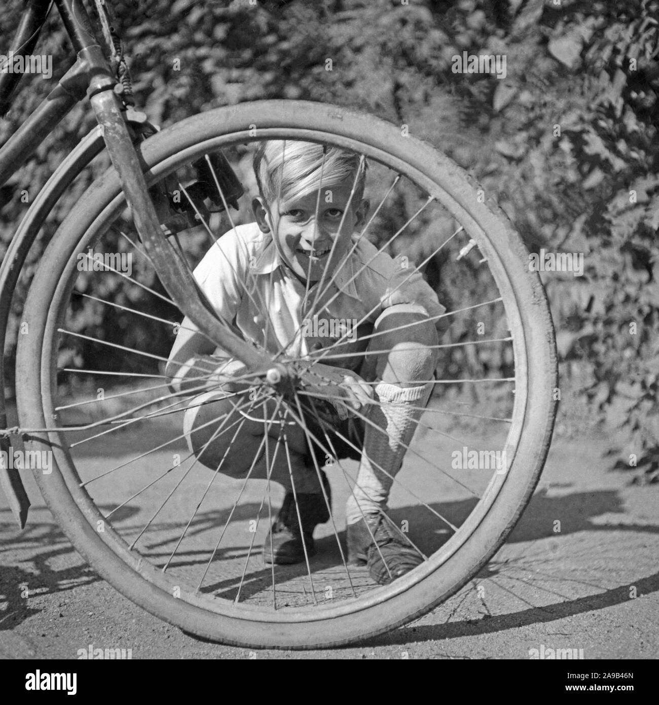 Ein Junge, der durch den Draht Rolle mit seinem Fahrrad direkt in die Kamera schauen, Deutschland 1957 Stockfoto