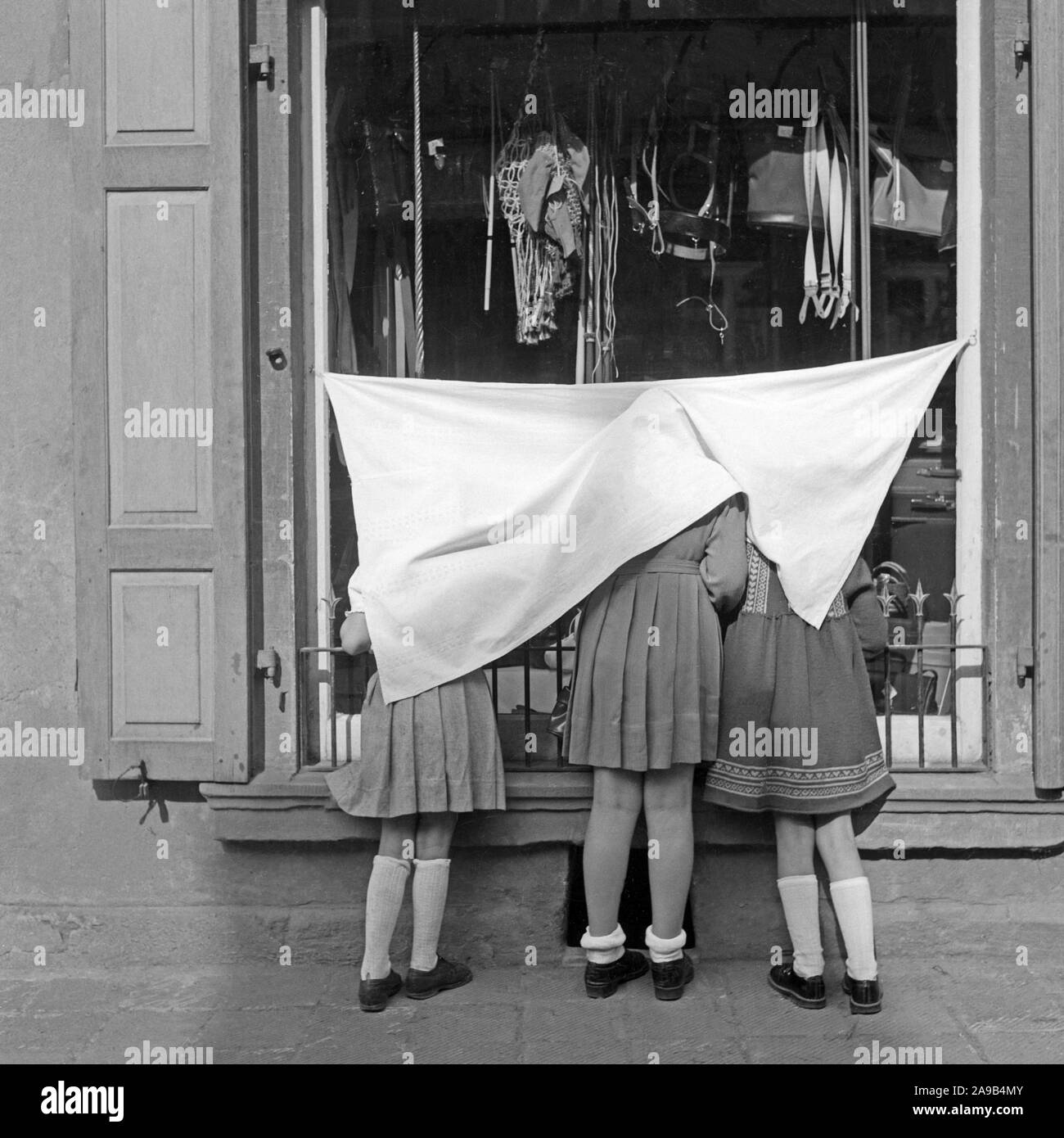 Drei Mädchen, beschichtet mit Vorhang, einen Blick in ein Schaufenster, Deutschland 1959 Stockfoto