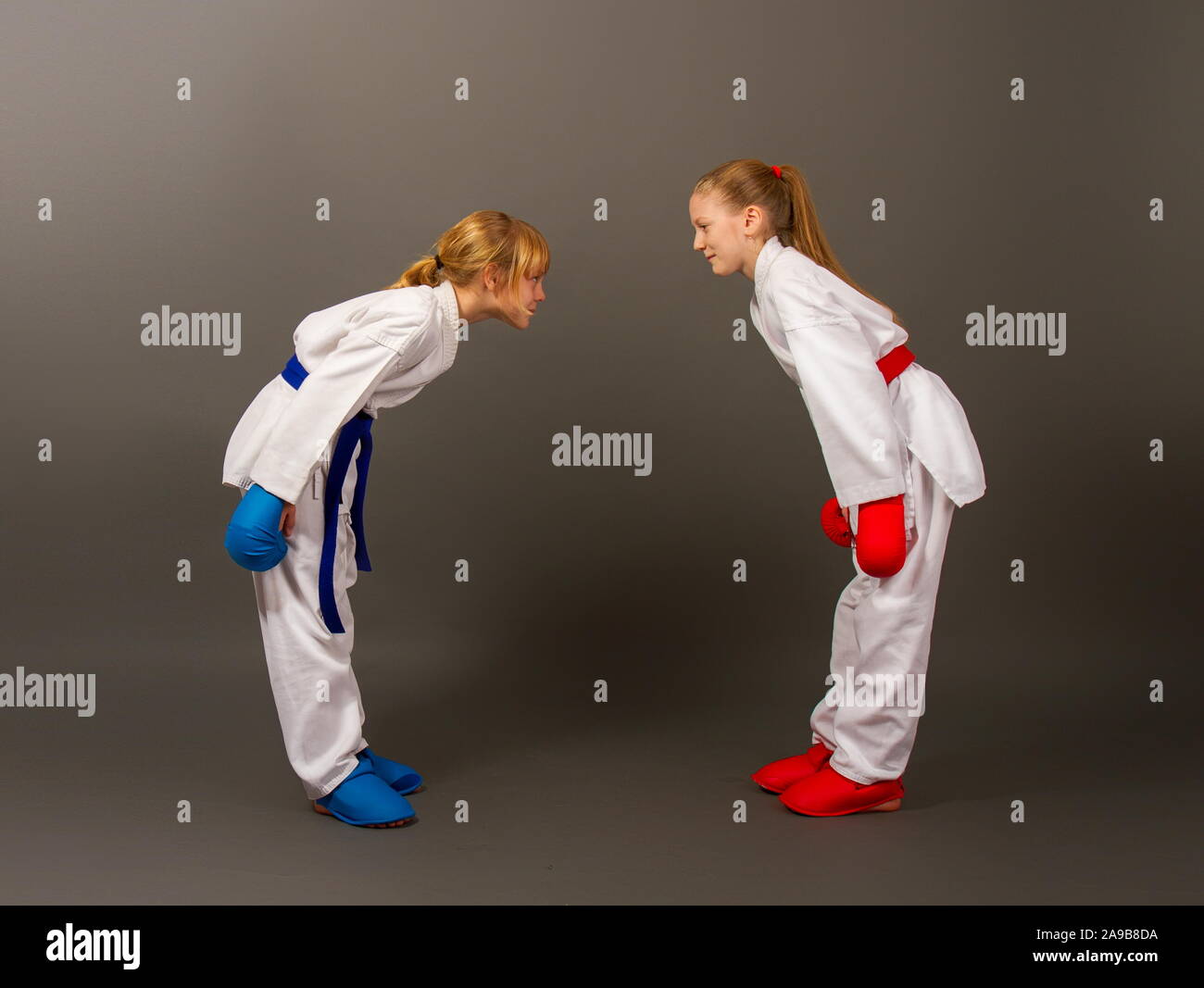 Zwei kleine Karate Mädchen in Kimonos und volle Sport Schutzausrüstung von roten und blauen Schleife als Zeichen des Respekts vor dem Kampf. Stockfoto