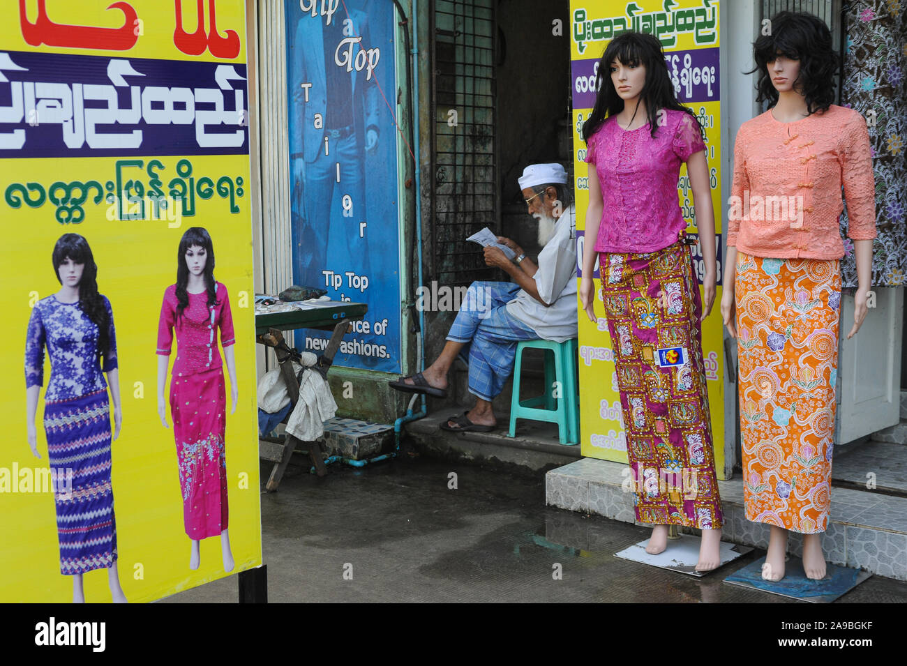 09.11.2015, Yangon, Myanmar - ein moslemischer Mann sitzt neben Mannequins von Frauen Fashion Store und liest. 0 SL 151109 D003 CARO.JPG [MODEL RELEASE: NEIN Stockfoto