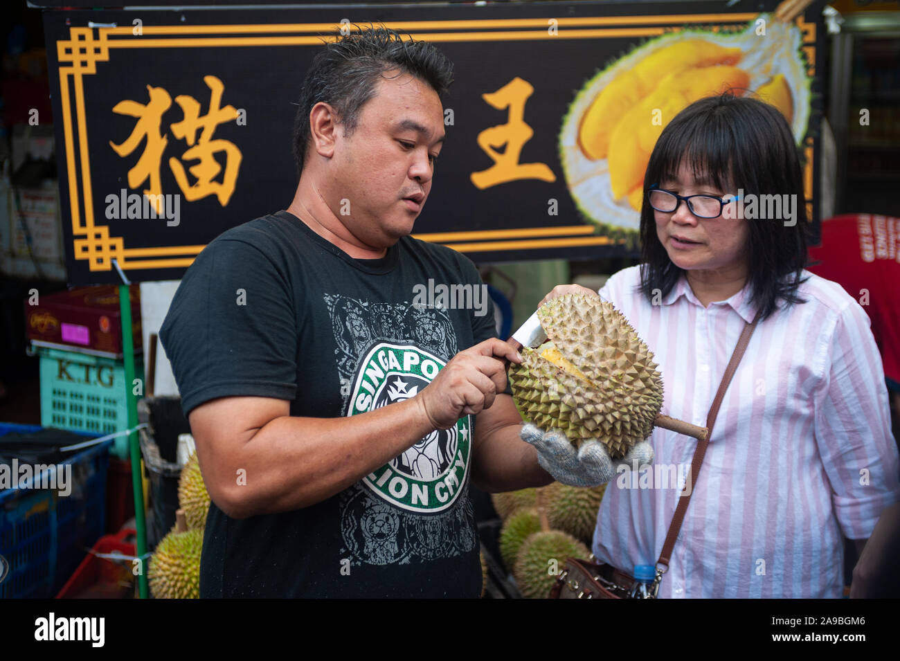 24.02.2019, Singapur, Singapur - ein Verkäufer öffnet sich eine frische Durian mit einem Messer auf einen Markt in Chinatown. 0 SL 190224 D 028 CAROEX.JPG [MODELL RELEAS Stockfoto