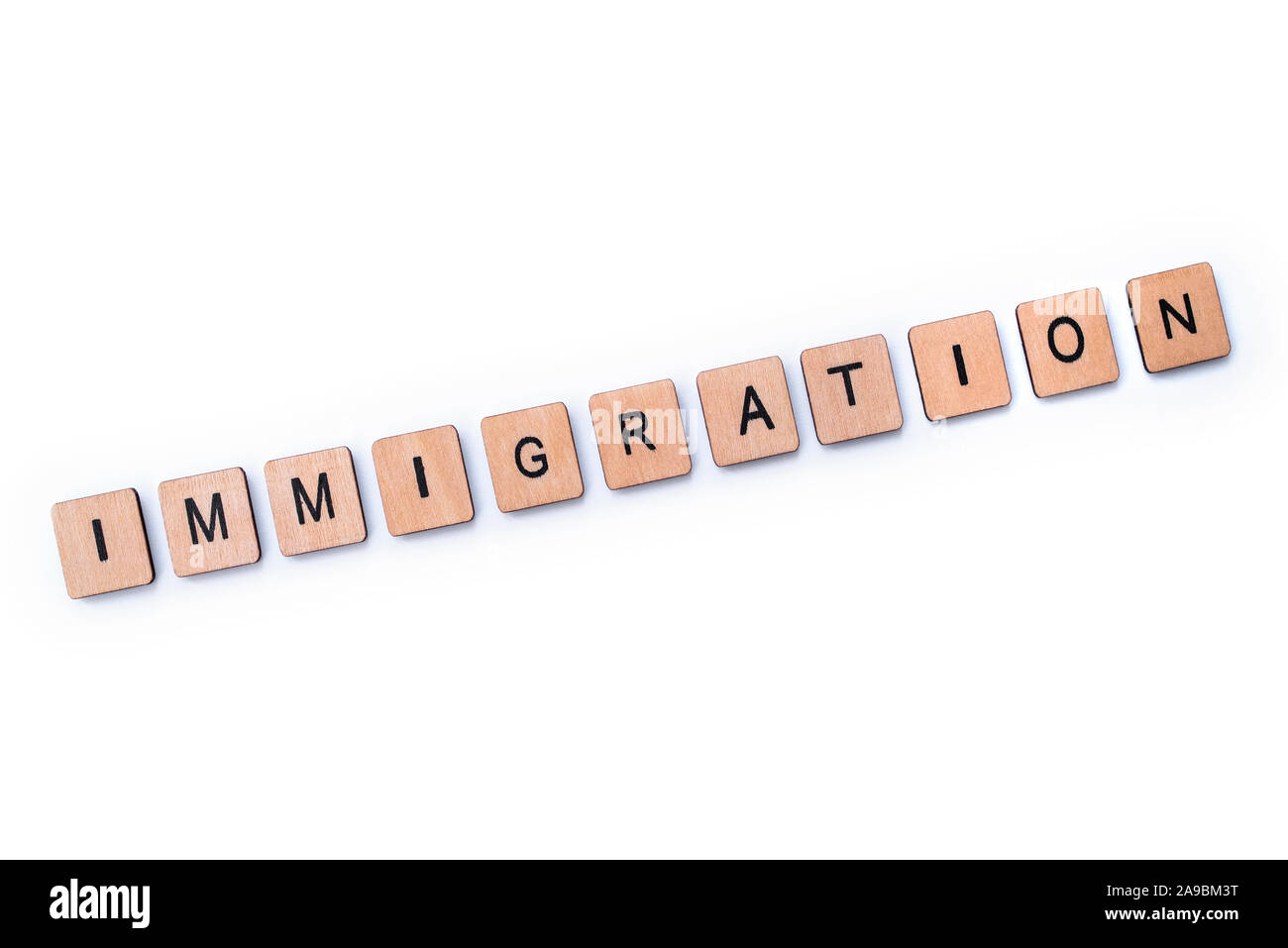 Das Wort "Einwanderung", Dinkel mit hölzernen Buchstabensteine über einem weißen Hintergrund. Stockfoto