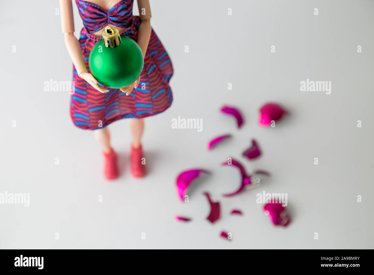In der Nähe der weiblichen Puppe holding Weihnachtskugel Neben gebrochen auf dem Boden minimal Kreativurlaub Konzept. Stockfoto
