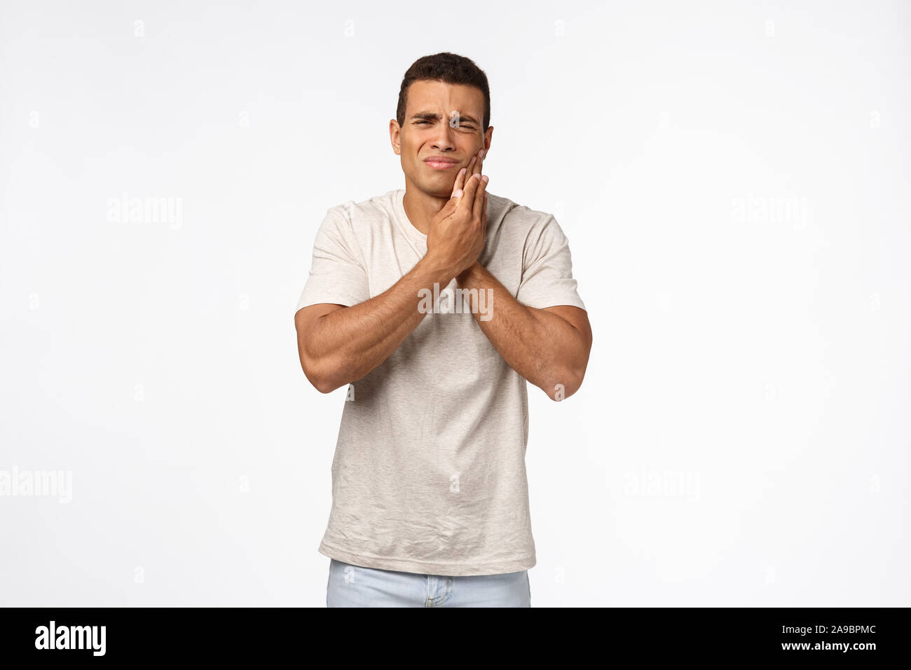 Verärgert stattliche männliche junge Menschen brauchen Termin Zahnarzt, berühren Wange und Schielen von schmerzliche Gefühl, Zahnschmerzen, schlechte Zerfall verursachen Schmerzen Stockfoto