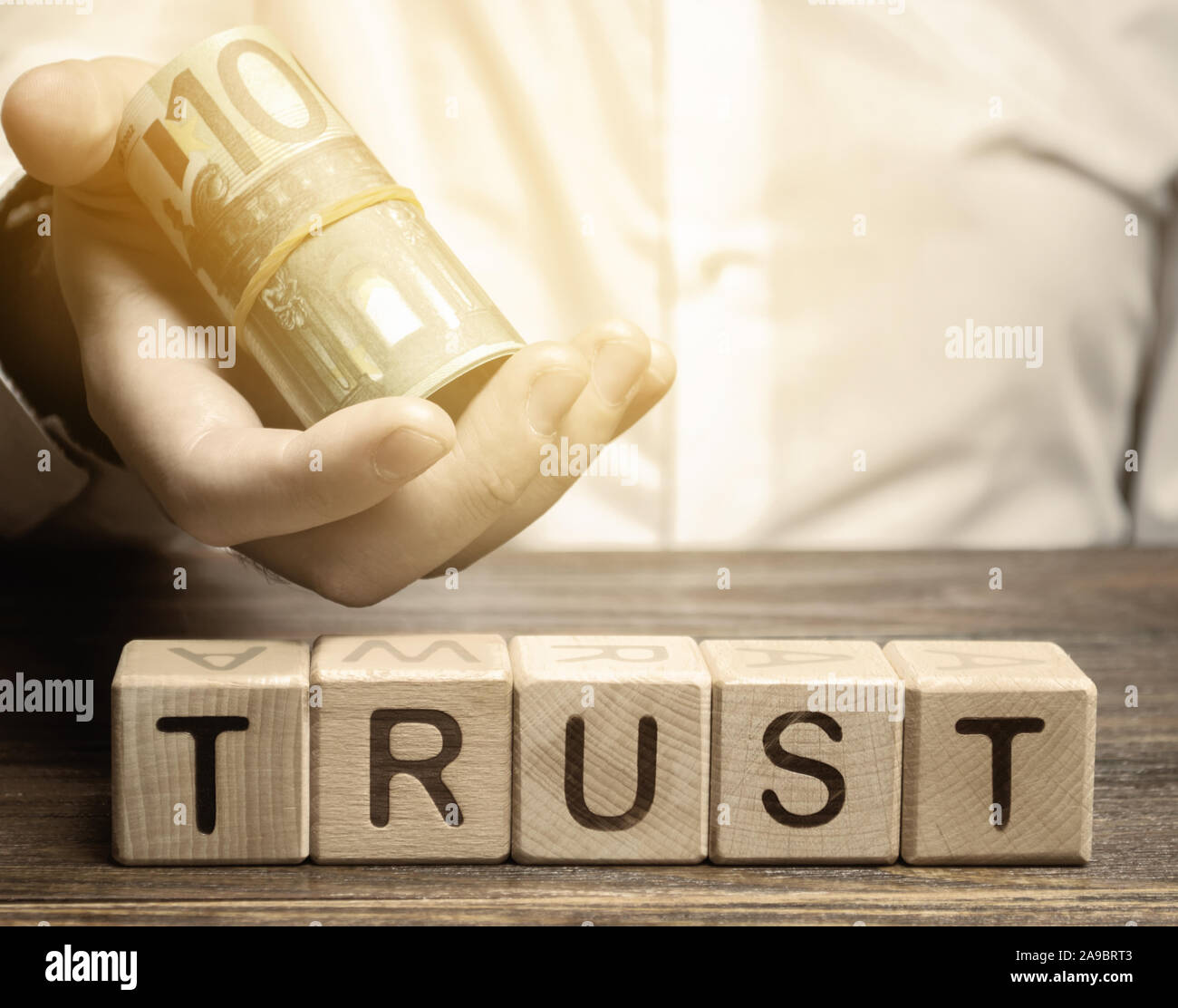 Holzblöcke mit dem Wort Vertrauen und Geld in die Hände eines Unternehmers. Vertrauensstellungen zwischen Geschäftspartnern, Freunden, Verwandten. Achtung Stockfoto