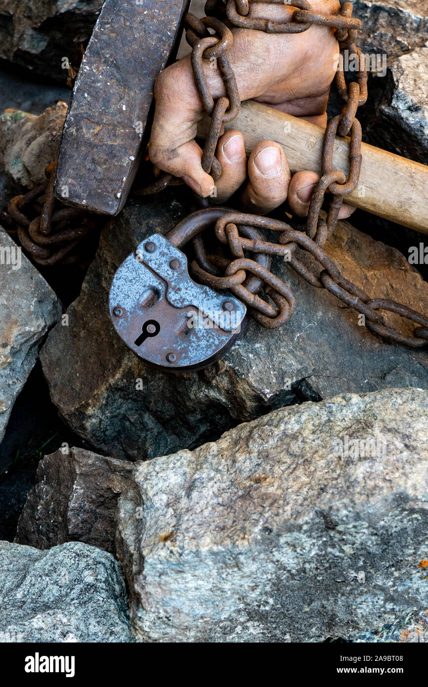 Slave chain gebundene Hände halten einen Hammer. Der Wunsch zu befreien. Die Fesseln zu brechen. Stockfoto