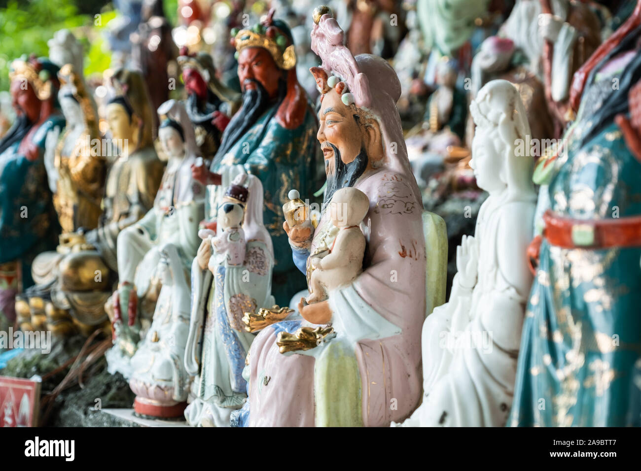 Hunderte von kleinen Statuen, die Götter der verschiedenen Religionen an einem Hügel in einem Coastal Park im Waterfall Bay, Hong Kong sitzen. Stockfoto