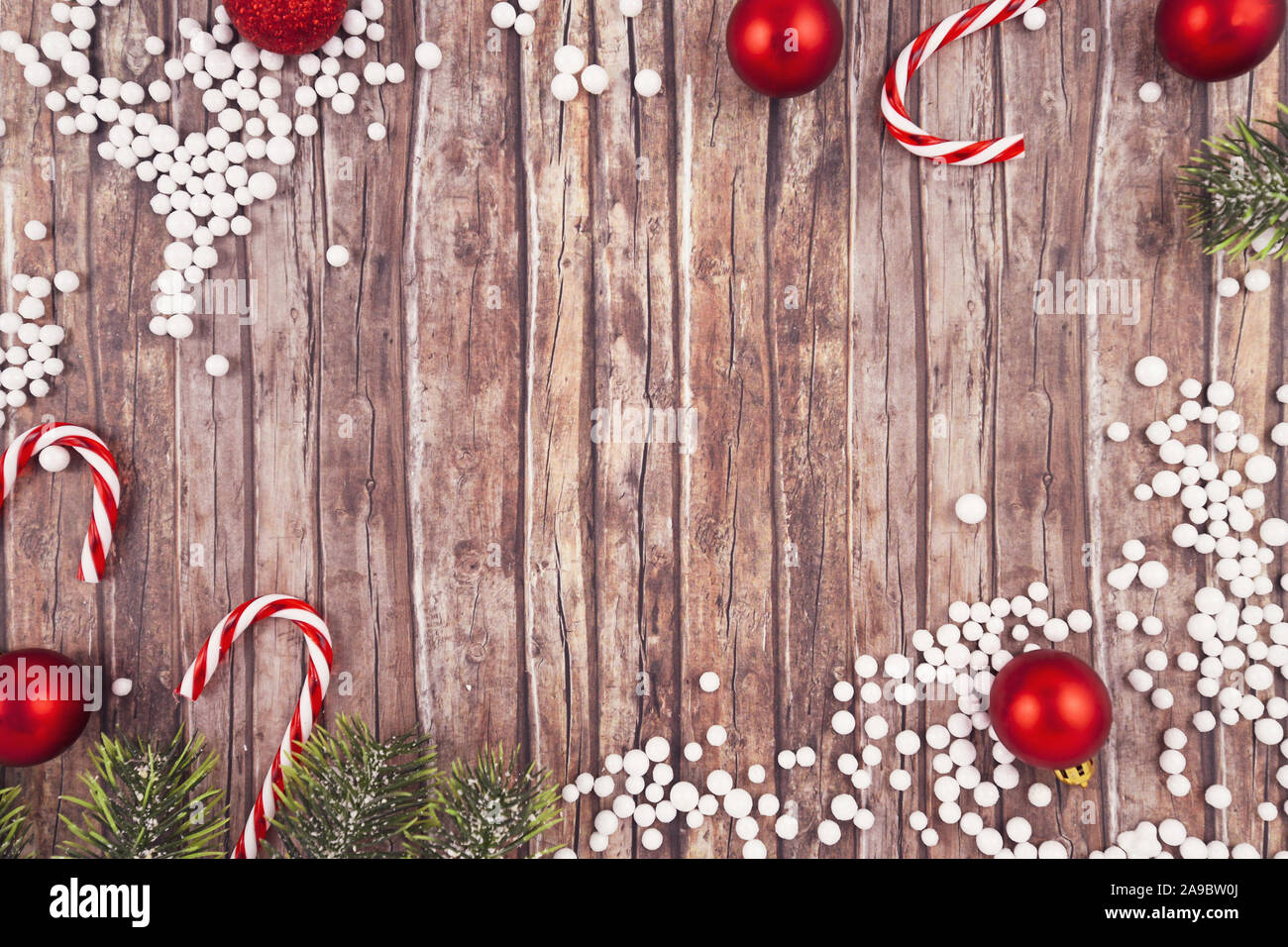 Saisonale Weihnachten flach mit traditionellen Red tree ornament Flitter, weißer Schnee Kugeln, Zuckerstangen und Tannenzweigen auf leere Holz- Kopie Raum zurück Stockfoto