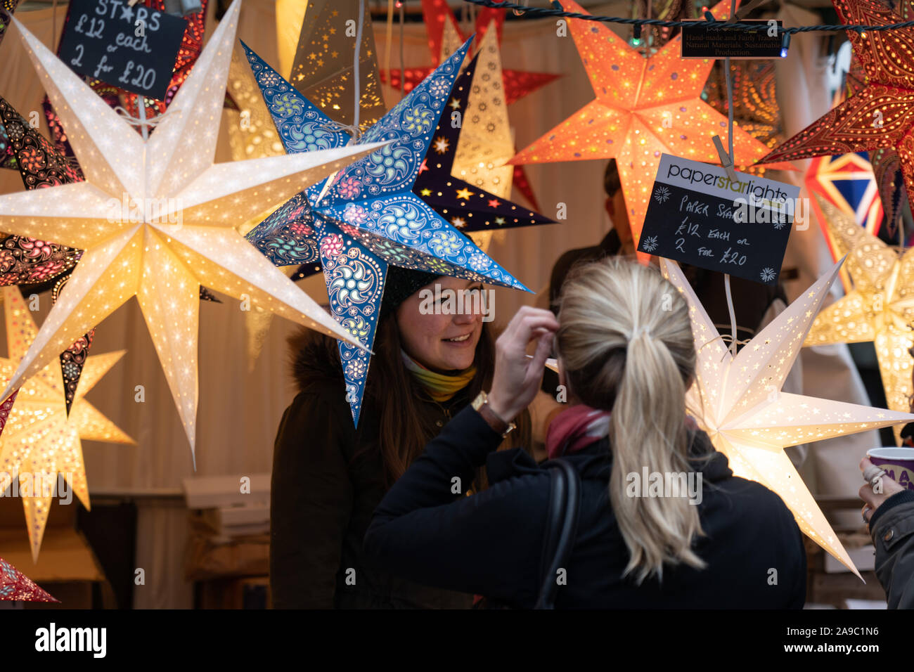 Auf dem Weihnachtsmarkt in Harrogate, North Yorkshire, England, verkauft eine Frau Diwali Star Lights und Laternen. Stockfoto