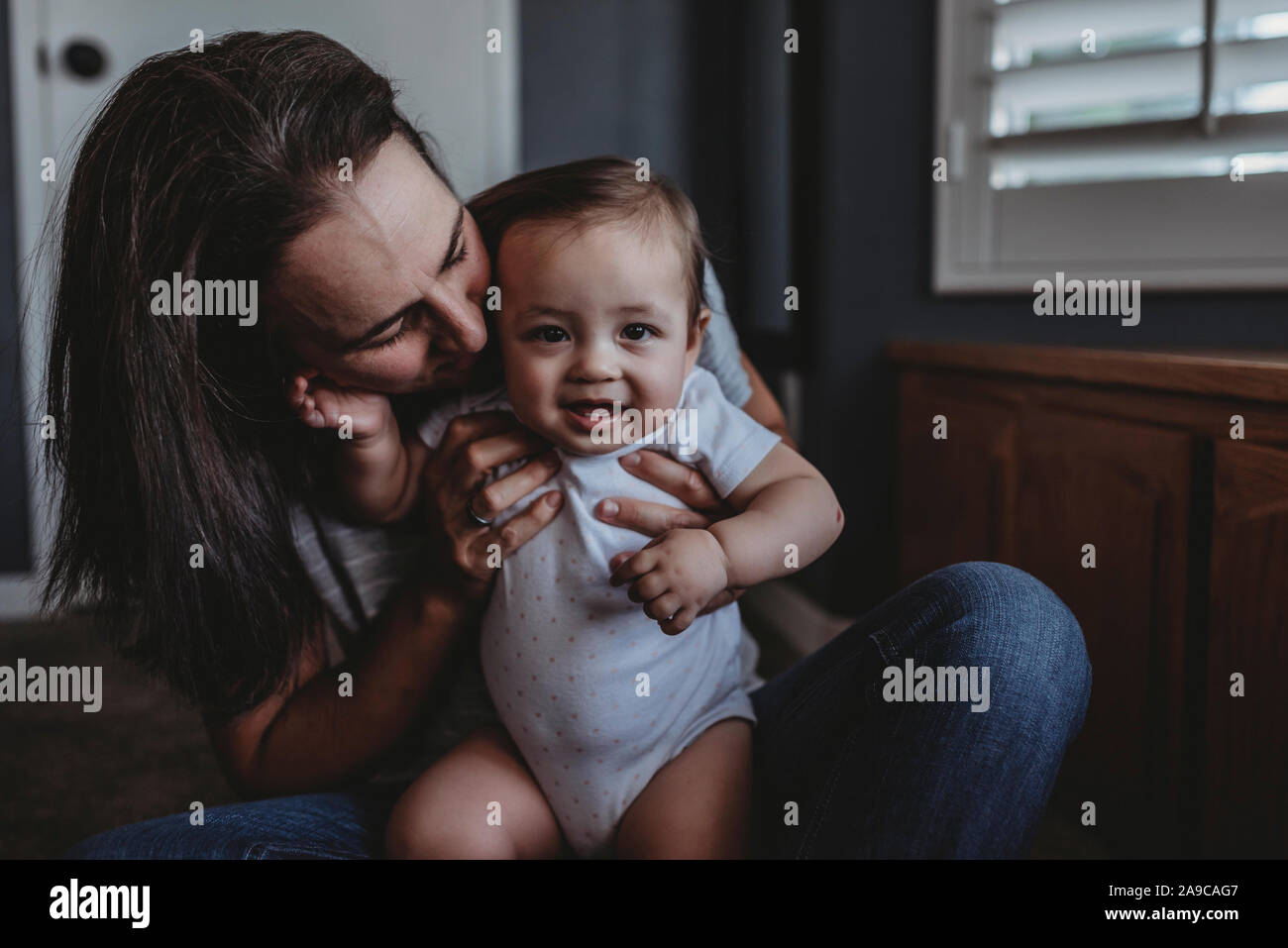 Mitte-40 â € ™ s Mama kuschelt smiling Baby auf dem Schoß Stockfoto