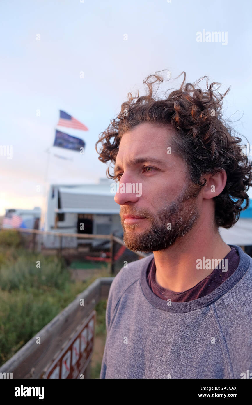 Mann mit lockigem Haar im Profil sich nachdenklich am Meer Stockfoto