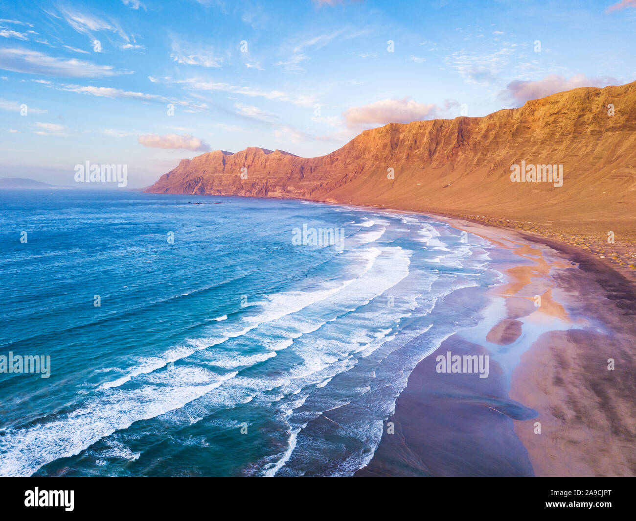 Famara Strand Surf spot Luftaufnahme der malerischen Landschaft von drohne in Lanzarote, Kanarische Inseln während der warmen sonnigen Sommertag, Ferienhäuser Stockfoto