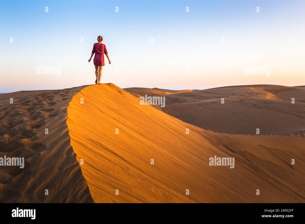 Mädchen gehen auf Sanddünen in dürren Wüste bei Sonnenuntergang und das Tragen von Kleidung, die malerische Landschaft der Sahara oder Naher Osten Stockfoto