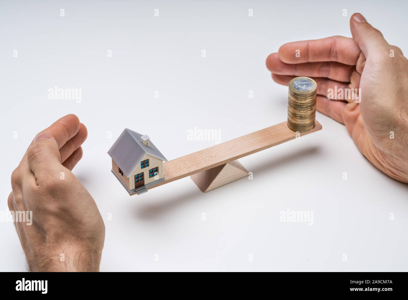 Des Menschen Hand Schutz der Balance von Haus und Stapel von Münzen auf Wippe Stockfoto