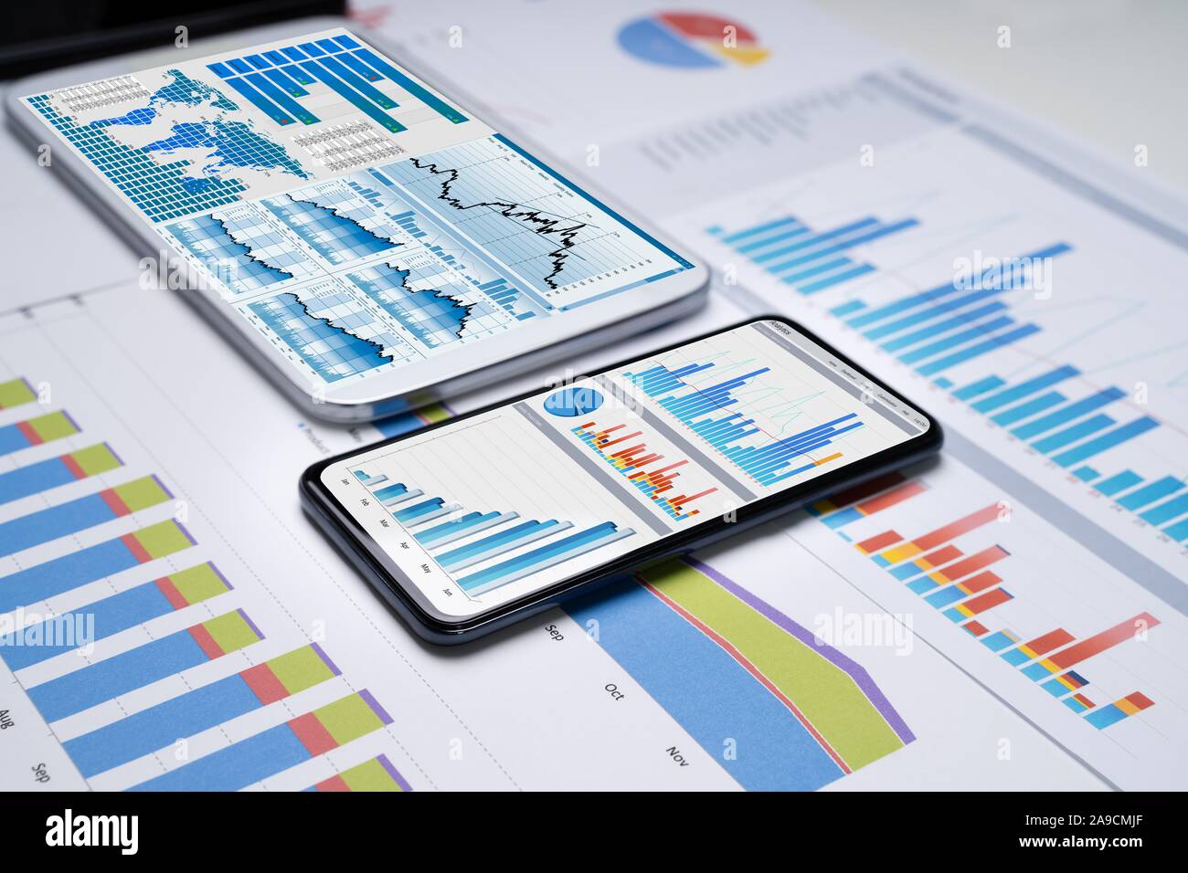 Nahaufnahme der Finanziellen Diagramme auf den Bildschirmen von vielfachen Smartphones auf Schreibtisch Stockfoto